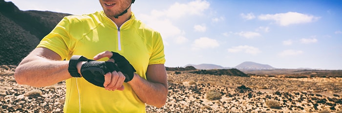 man in desert, wearing athletic clothes, looking at smart watch